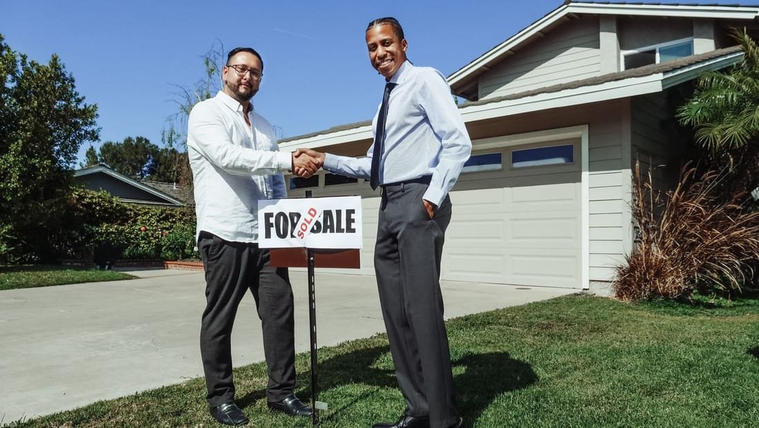 Agents in front of a home with a sold sign